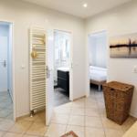 Flur mit Tür zu Bad, Schlafzimmer und Garderobe. Wandbild und Korb sind sichtbar.