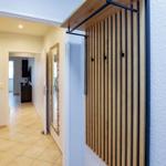 Eingangsbereich mit Holzgarderobe und Blick in den Flur mit Spiegel und Schrank.