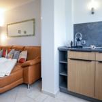 Wohnbereich mit braunem Sofa und Küchenzeile mit Kaffeemaschine.