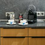 Küchenarbeitsplatte mit Kaffeemaschine, Kaffeetassen und Kaffeevorrat.