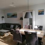 Living and dining area with sofa, table, and chairs. Wall art and lighting visible.