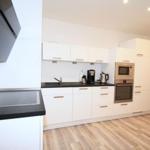Modern kitchen with white cabinets, black countertop, and built-in oven.
