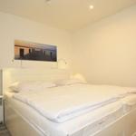 Bedroom with double bed, nightstand, and wall picture.