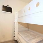 Room with bunk bed, wall-mounted TV, and ladder.