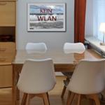 Dining room with wooden table, white chairs, and wall picture with sea and text.