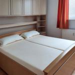 Bedroom with double bed, wooden furniture, and window with orange curtains.