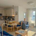 Kitchen-living area with dining space, blue striped armchair, and water view