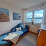 A room with a sofa, water view from the window, and wall pictures.