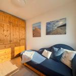 Bedroom with wooden wardrobe and sofa with cushions and blanket.