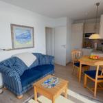 Living and kitchen area with sofa, dining table, and kitchen cabinets.