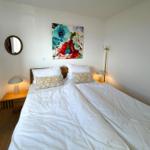 A bedroom with a double bed, two bedside tables, and wall decor.