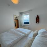 Bedroom with double bed, window overlooking water, and wall shelf in boat shape.