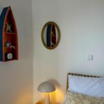 Bedroom with bed, nightstand, and wall shelf shaped like a boat.