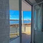 View of a lake from the balcony with glass door and white railings.