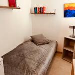 A bedroom with a single bed, wall shelves, and a bedside lamp.