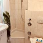 Bathroom with shower, sink, and toilet. Tiled walls and floor.