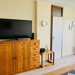 Living room with wooden cabinet, TV, and door