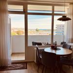 Dining room with harbor and sea view. Round table, chairs, balcony with seating area.