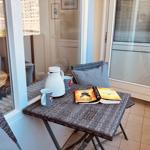 Balcony with table, chairs, and book. View of high-rise buildings.