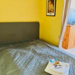 Bedroom with bed, TV, and wooden cabinet. Yellow walls and comfortable furnishings.