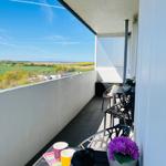 Balkon mit Tisch, Stühlen und Blick auf grüne Landschaft.
