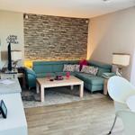 Wohnzimmer mit Sofa, Couchtisch und Holzboden. Hintergrundwand aus Steinoptik.