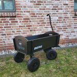 Black wagon with four wheels in front of brick wall