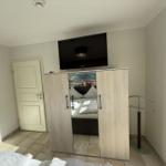 Bedroom with wardrobe, TV, and bed. Door and clothes stand are visible.