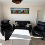 Living room with black sofa, two chairs, and white table. Wall art with colorful umbrellas.