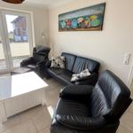 Living room with black leather furniture, white table, and wall art with umbrellas.