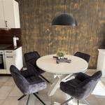 Round table with four chairs and pendant lamp against gold wall.