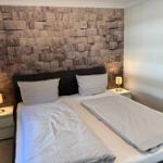 Bedroom with double bed, stone wall, and nightstands with lamps.