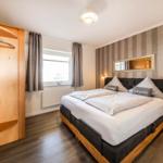 Bedroom with double bed, wardrobe, and window with curtains.