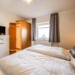 Bedroom with double bed, wardrobe, window, and wall-mounted TV.