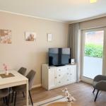 Living and dining area with TV, table, chairs, and armchair. Window with view of balcony.