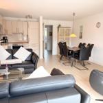 Living and dining area with black leather furniture and modern kitchen.