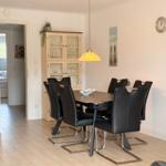 Dining room with table, six chairs, and glass cabinet. Pendant lamp and wall clock visible.