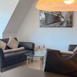 Living room with sofa, armchair, and glass table under a ceiling lamp.