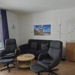 Living room with sofa, two chairs, table, and window with sea view.