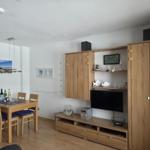 Living and dining area with wooden furniture, TV, and kitchenette.
