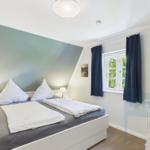 Schlafzimmer mit Doppelbett, Fenster und Schrank.
