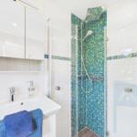 Badezimmer mit Dusche, Waschbecken und Spiegel