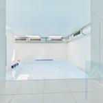 Indoor pool with white tiles and ceiling ventilation system
