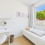 A bedroom with window, desk and bed. Three pictures hang on the wall.