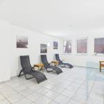 Room with lounge chairs, benches, and windows. Wall art and tiled floor.
