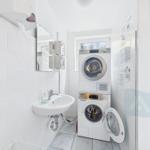 Washing room with washer and dryer, mirror, and towel dispenser.