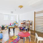 Childrens room with toys, tables, chairs, and gymnastic equipment.