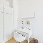 Desk with chair, mirror, and lamp in a room with wardrobe.