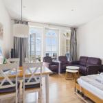 Apartment with dining area, sofa, armchairs, and sea view.