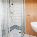 Dusche mit Glaswand, blauen Fliesen und Waschbecken
